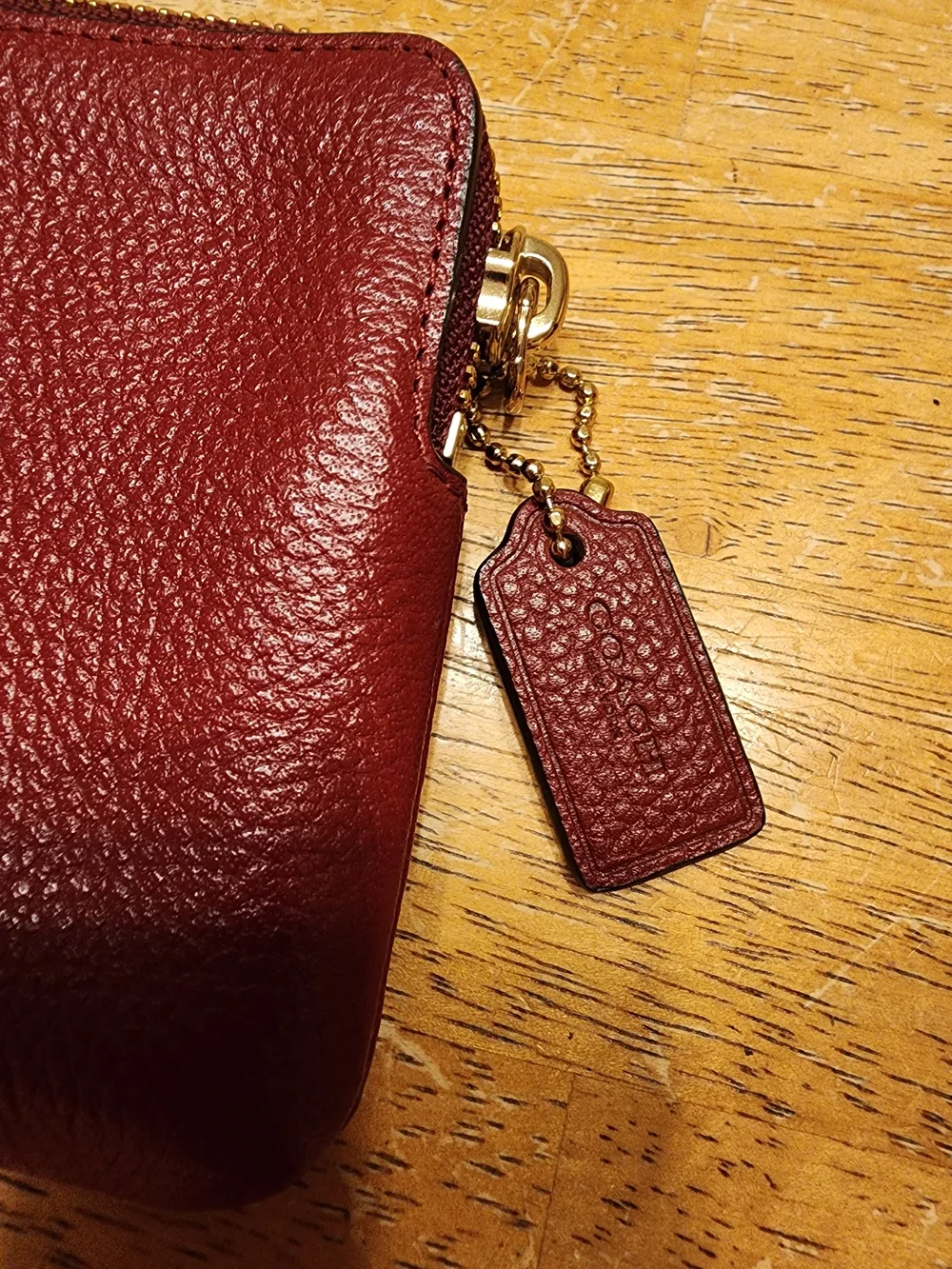 red polished pebble leather Coach wristlet, featuring gold-tone hardware